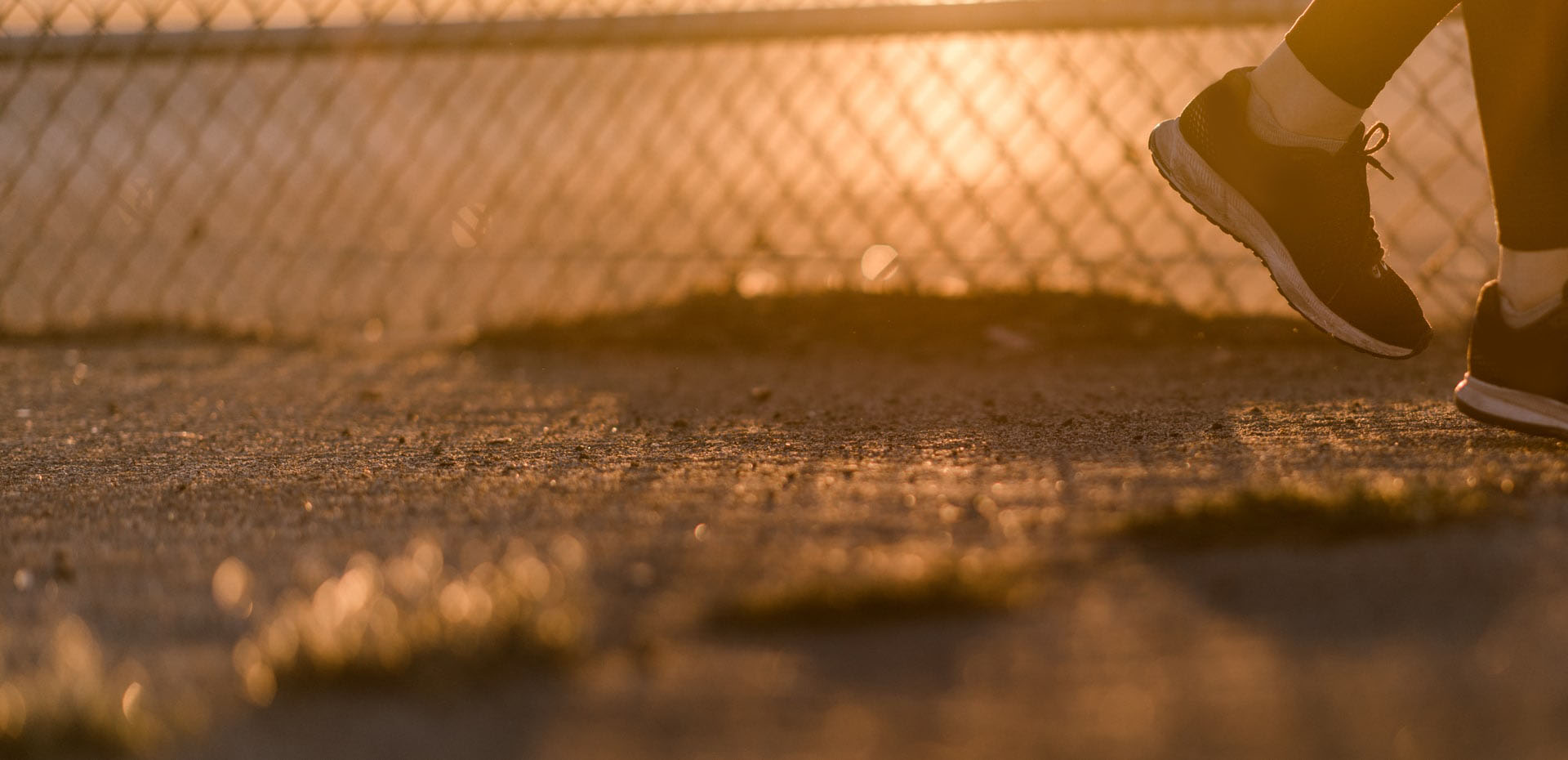 A runner mid-stride on a path at golden hour